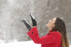 Woman in red throwing snow in the air in winter